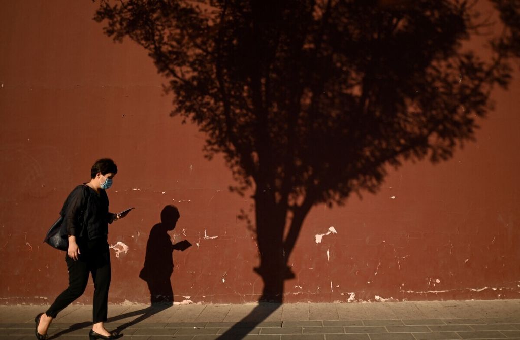 Seorang wanita menggunakan ponselnya saat berjalan di sepanjang jalan di Beijing, China, 10 Juni 2021.