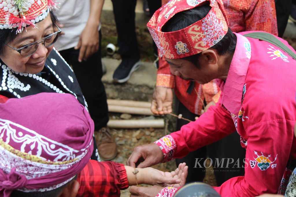 Menteri Lingkungan Hidup dan Kehutanan Siti Nurbaya Bakar diterima secara adat dengan mengikat gelang (<i>tongang</i>) di pergelangan tangannya, di Desa Kinipan, Kecamatan Batang Kawa, Kabupaten Lamandau, Kalimantan Tengah, Sabtu (7/9/2024). Ikat <i>tongang </i>merupakan tanda penerimaan dan ikatan penuh kasih masyarakat adat Dayak Tomun di Lamandau, Kalteng, kepada tamu.