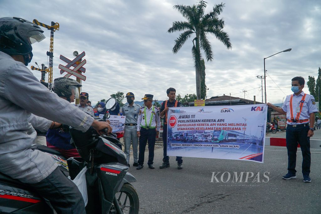 Petugas membentangkan spanduk imbauan kepada warga dalam kampanye keselamatan dalam rangka Hari Perhubungan Nasional di pelintasan sebidang depan Stasiun Padang, Kecamatan Padang Timur, Kota Padang, Sumatera Barat, Sabtu (27/8/2022). 