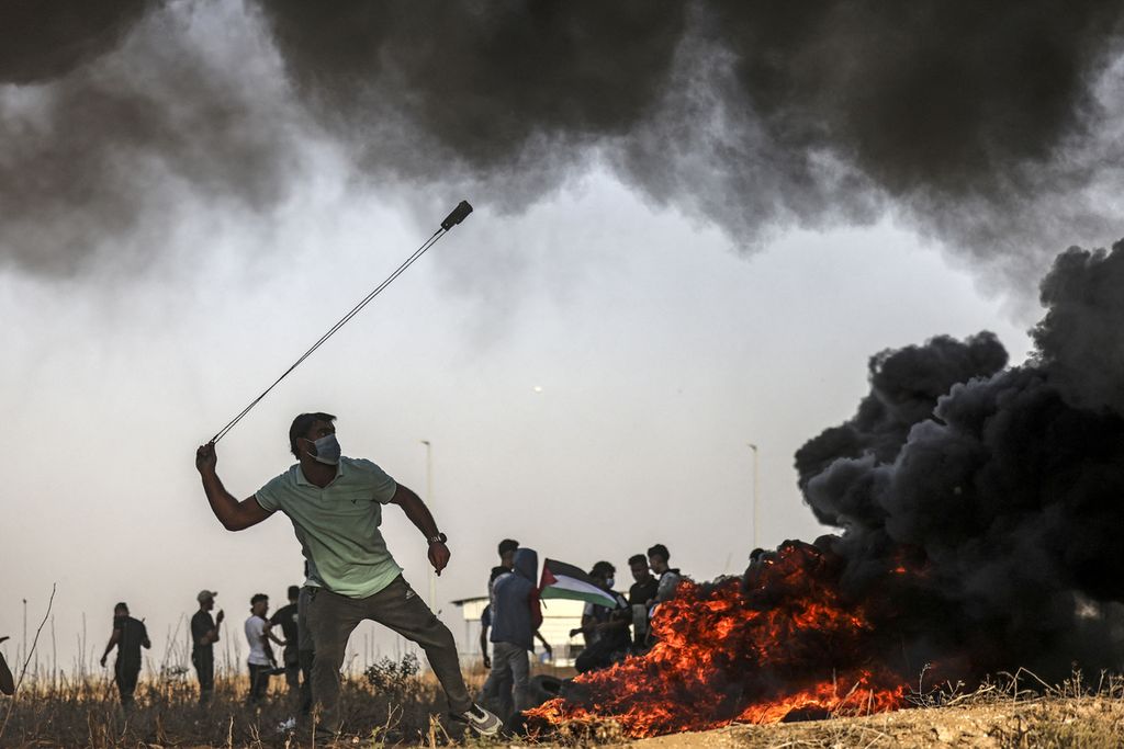 Seorang warga Palestina menggunakan <i>slingshot</i> saat melontarkan batu melewati perbatasan dengan Israel di Jalur Gaza, Selasa (25/10/2022).