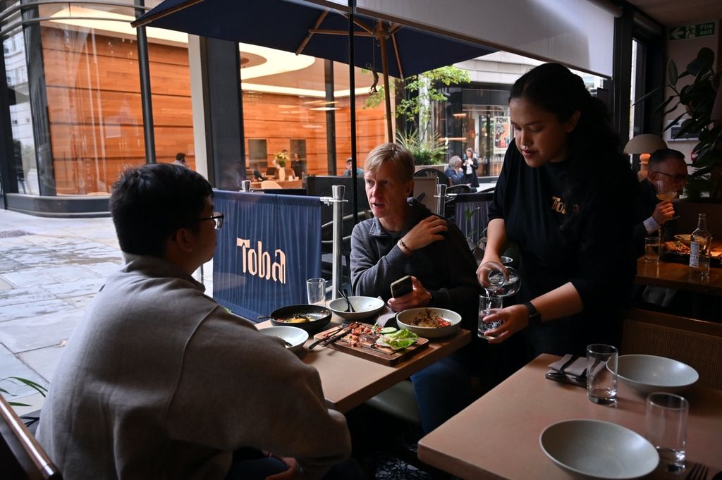 Seorang pramusaji menuang minuman di restoran Toba, St James's Market, London, Inggris, Kamis (12/10/2023). 