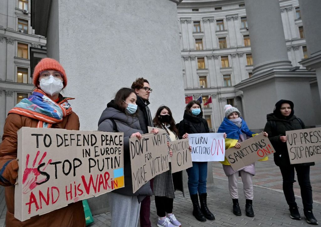 Para pengunjuk rasa membawa poster berisi kecaman terhadap Presiden Rusia Vladimir Putin dan negaranya dalam unjuk rasa di luar Kantor Menteri Luar Negeri Ukraina di Kiev, Ukraina, Senin (21/2/2022). 