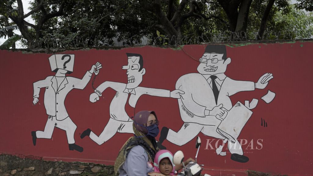 Warga melintasi mural kritik terhadap koruptor yang melarikan uang negara di Jatisampurna, Kota Bekasi, Selasa (29/12/2020). Meski hukuman buat koruptor sudah dijatuhkan, hingga kini perbuatan merugikan negara tersebut masih sering dilakukan tanpa rasa takut. 