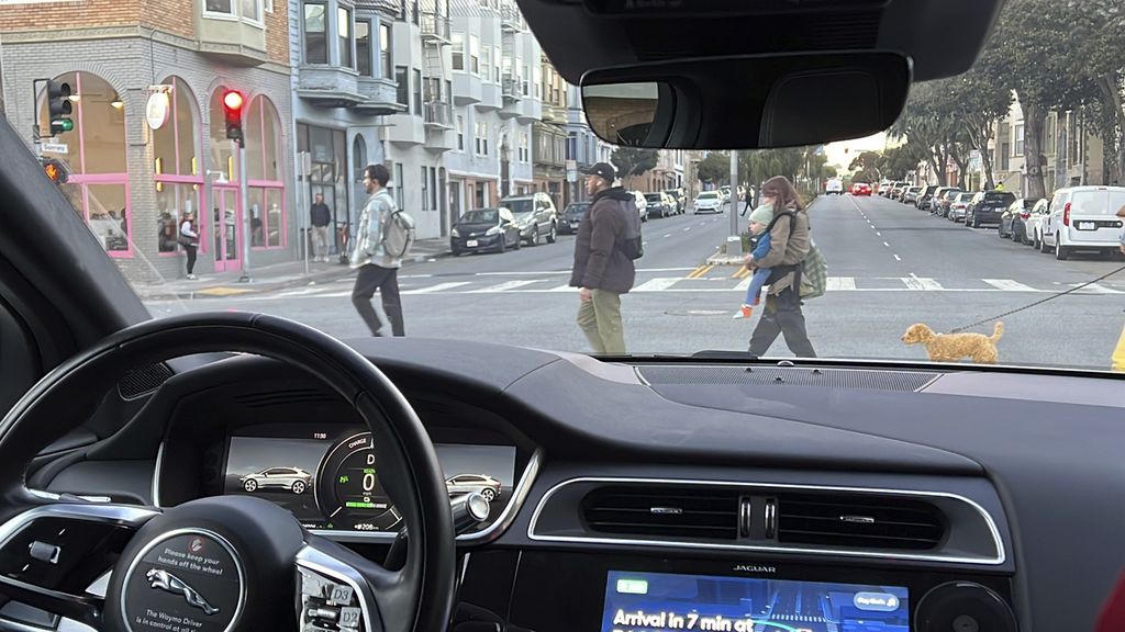 Robotaxi Waymo yang dikembangkan Google berhenti saat sejumlah pejalan kaki menyeberang jalan saat uji coba di San Francisco, Amerika Serikat,  15 Februari 2023.  