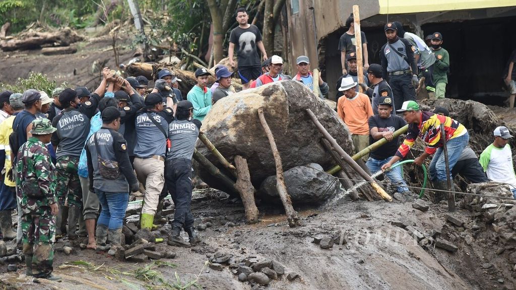 Warga bersama-sama memindahkan batu besar yang terbawa banjir bandang Desa Bulukerto, Kecamatan Bumiaji, Kota Batu, Jawa Timur, Jumat (5/11/2021). 