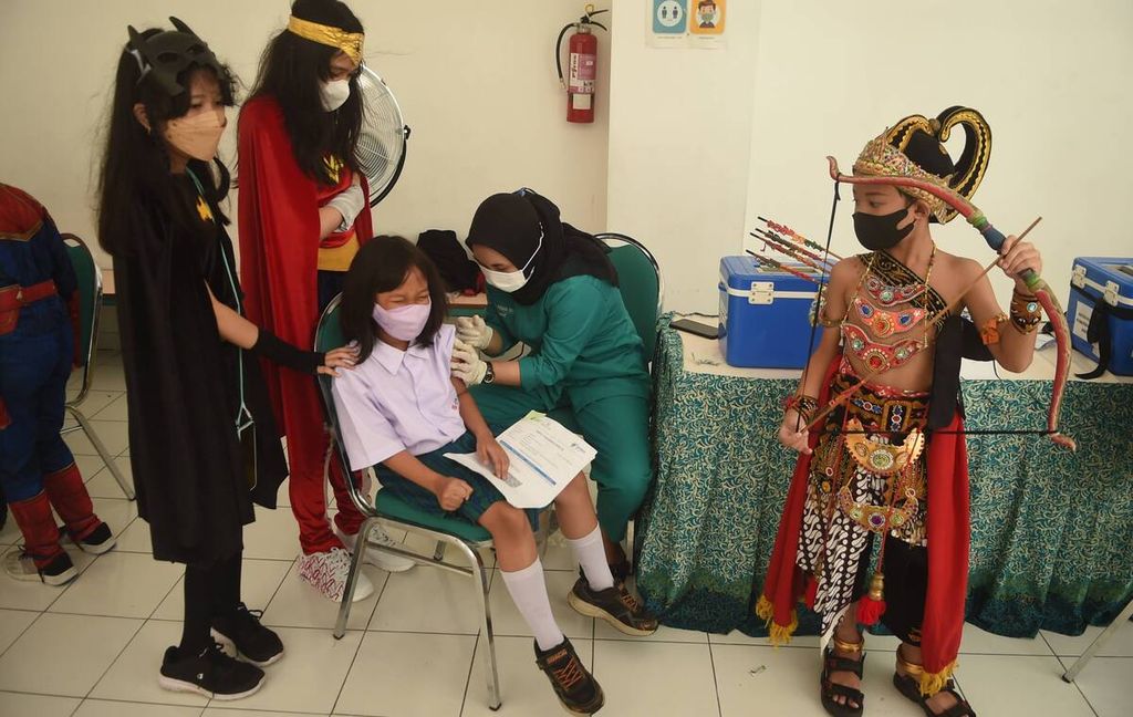 Siswa berkostum wayang dan <i>superhero </i>menemani temannya menjalani vaksinasi dosis kedua di SD Pembangunan Jaya 2, Kabupaten Sidoarjo, Jawa Timur, Kamis (17/2/2022). 