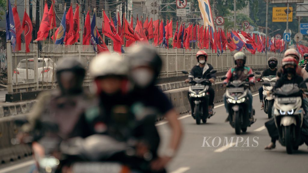 Warga melintasi bendera partai politik Partai Demokrasi Indonesia Perjuangan (PDI-P) di Jalan Tambak, Jakarta Pusat, Minggu (19/6/2022). 