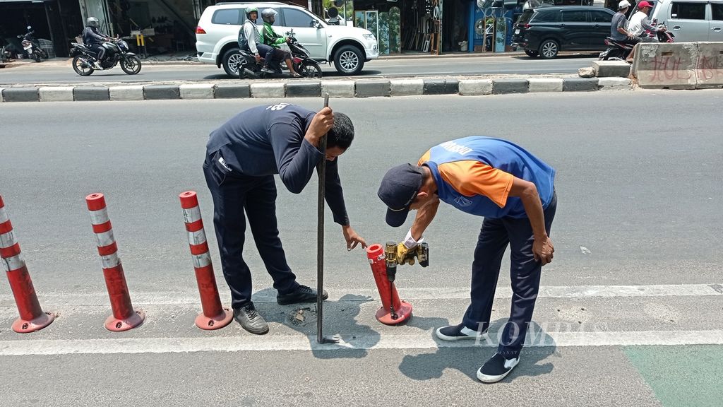 Petugas dari Cepat Respons Masyarakat Dinas Perhubungan DKI Jakarta mencopot <i>stick cone</i> lajur sepeda yang rusak di samping Menara BNI, Jakarta Pusat, Rabu (18/10/2023). <i>Stick cone</i> rusak itu bakal diganti mata kucing atau marka timbul yang memantulkan cahaya ketika terkena sinar lampu kendaraan.