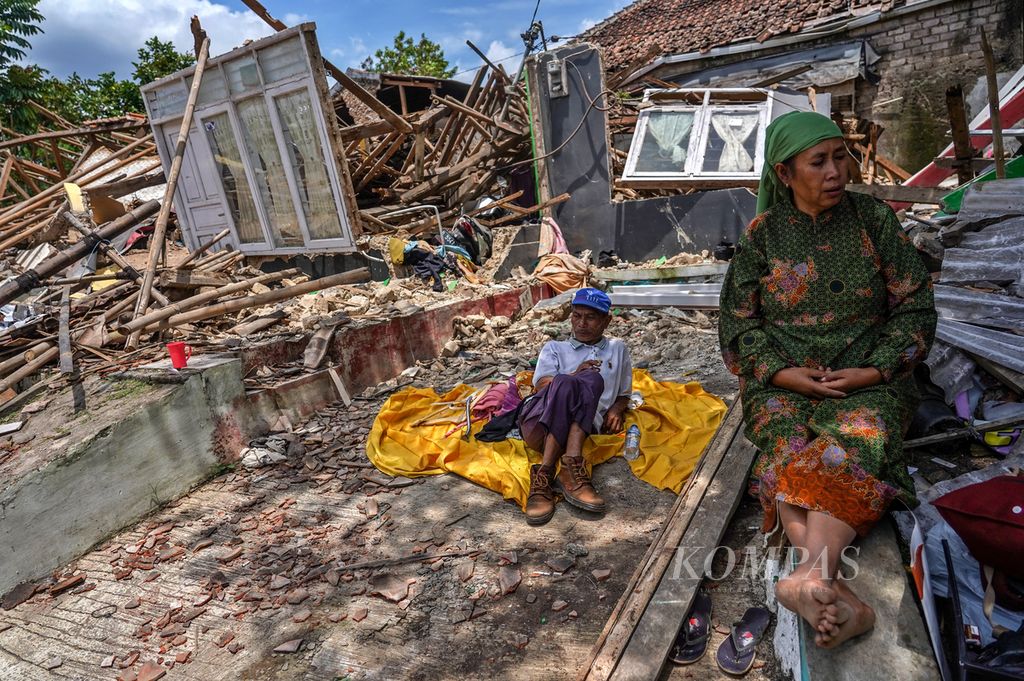 Ela (58) bersama keluarganya duduk di depan rumahnya yang runtuh akibat gempa di Kampung Longkewang, Desa Gasol, Cugenang, Kabupaten Cianjur, Jawa Barat, Selasa (22/11/2022).  