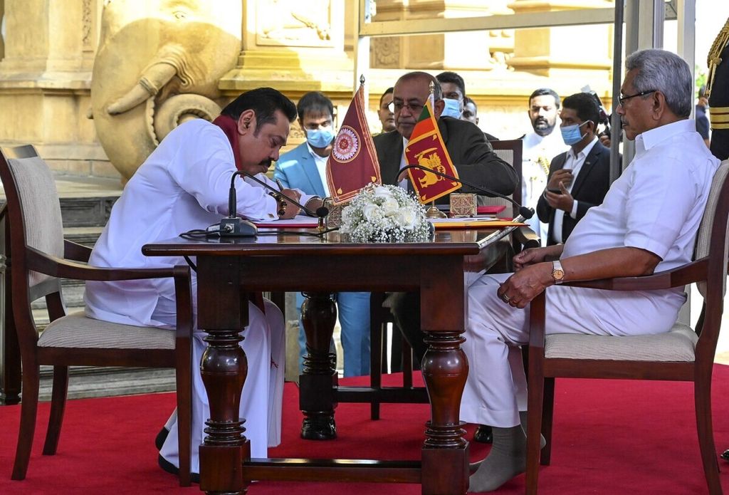 Perdana Menteri Sri Lanka Mahinda Rajapaksa (kiri) mengambil sumpah di depan adiknya, Presiden Sri Lanka Gotabaya Rajapaksa (kanan)  di Candi Budha Kelaniya Mahaviharaya, luar Kota Kolomobo, 9 Agustus 2020. (Photo by Ishara S. KODIKARA / AFP)