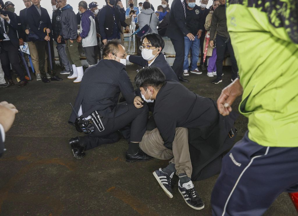 Seorang pria terjatuh di tanah setelah dibekuk petugas keamanan di Wakayama, Jepang, 15 April 2023. Pria itu diduga sebagai pelaku pelemparan bom asap ke arah Perdana Menteri Fumio Kishida yang akan berpidato di sebuah pelabuhan. 