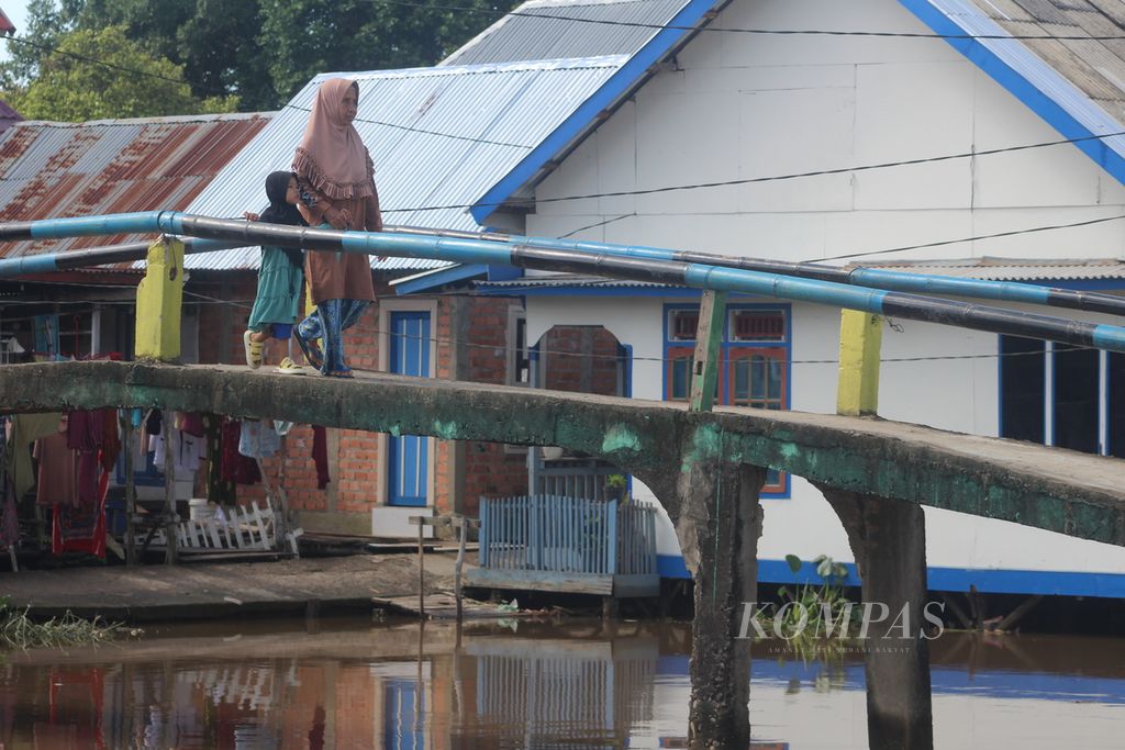 Warga Kampung Sungai Pedado, Kecamatan Kertapati, Palembang, Sumatera Selatan, sedang berjalan di atas jembatan, Sabtu (13/5/2023). Daerah ini merupakan daerah pinggiran Kota Palembang yang sebagian besar penduduknya bekerja sebagai buruh bangunan.