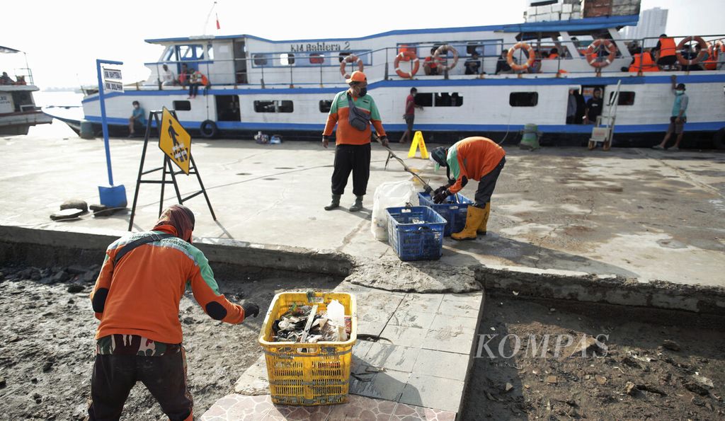 ILUSTRASI. Petugas membersihkan lingkungan dari sampah sisa rob di Pelabuhan Kali Adem, Penjaringan, Jakarta Utara, Minggu (30/5/2021). 