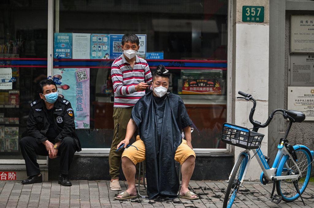 Seorang pria cukur rambut di sebuah jalan di Distrik Jing'an, Shanghai, China, seiring pembukaan wilayah setelah penguncian ketat selama dua bulan, 30 Mei 2022. 
