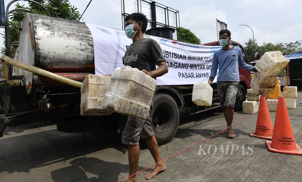  Workers carry empty jerry cans to be filled with bulk cooking oil during the distribution of bulk cooking oil specifically for traders at Pasar Anyar, Tangerang City, Banten, Tuesday (29/3/2022). A total of 10 tons of bulk cooking oil transported by two tank cars are sold specifically to traders who have been previously registered.