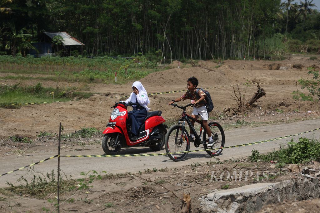 Pelajar menutupi matanya agar tidak kemasukan debu saat melintasi lokasi pembangunan proyek Jalan Tol Solo-Yogyakarta di Desa Gatak, Ngawen, Klaten, Jawa Tengah, Rabu (14/9/2022). 