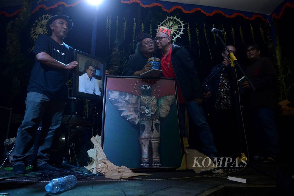 Mantan wartawan harian <i>Kompas</i>, Thomas Pudjo (kedua dari kiri), terharu saat menerima berbagai hadiah dari rekan serta para seniman di Omah Petroek, Desa Hargobinangun, Pakem, Sleman, DI Yogyakarta, Minggu (26/11/2017).