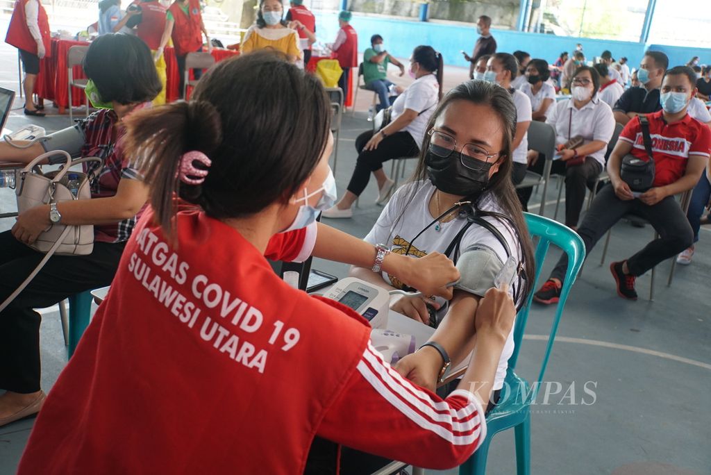 Petugas penapisan Satuan Tugas Covid-19 Sulawesi Utara mengukur tekanan darah calon penerima vaksin, Rabu (24/3/2021), dalam vaksinasi massal di Manado. 