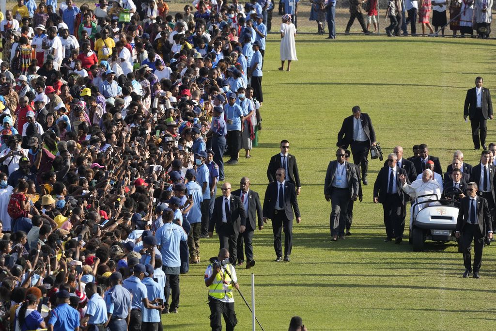 Paus Fransiskus, di sebelah kanan kereta, didorong melewati ribuan orang sebelum ia mengadakan misa suci di Stadion Sir John Guise di Port Moresby, Papua Niugini, Minggu (8/9/2024). 