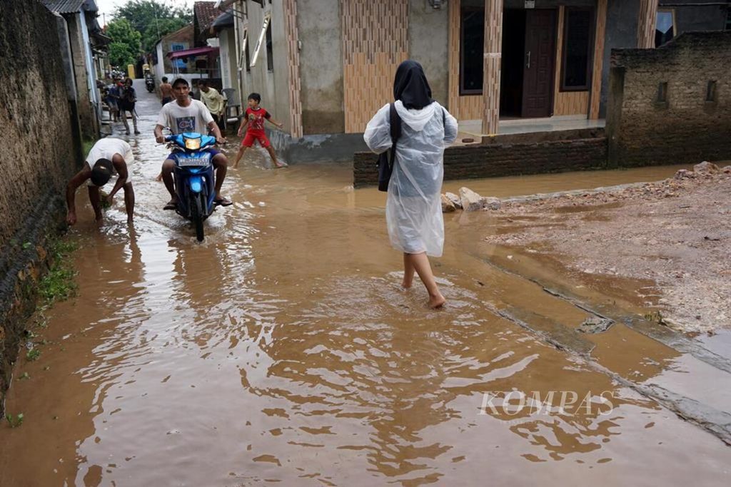 Warga di Kelurahan Kalibalau Kencana, Kecamatan Kedamaian, Kota Bandar Lampung, Lampung, beraktivitas di tengah banjir yang mulai surut, Rabu (23/5/2018). Banjir akibat luapan Sungai Way Balau terjadi setelah hujan deras mengguyur daerah tersebut lebih dari enam jam.