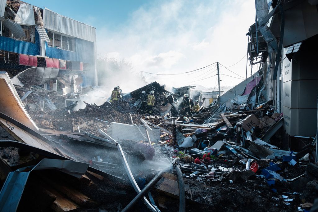 Petugas pemadam kebakaran berdiri tak jauh dari sebuah bangunan pasar yang rusak akibat serangan artileri berat di Bakhmut, Ukraina timur, Kamis (21/7/2022). 