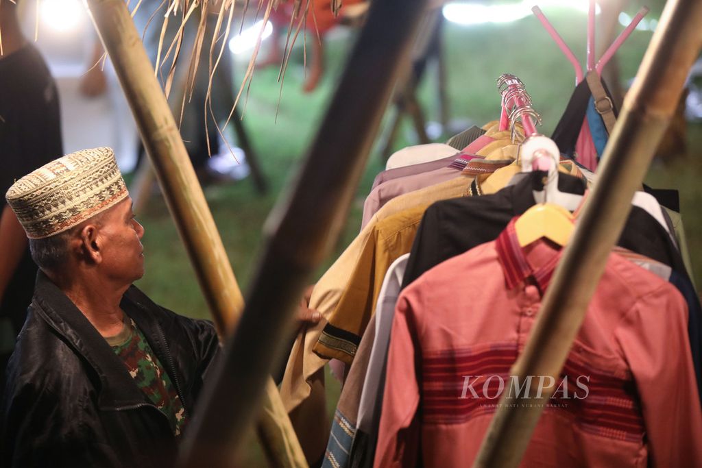 Pengunjung memilih baju dari tenun dalam bazar di tempat acara malam Apresiasi Desa Budaya 2023 di Desa Pringgasela Selatan, Pringgasela, Lombok Timur, Nusa Tenggara Barat, Rabu (20/12/2023).