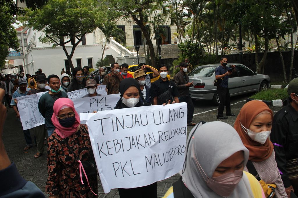 Sejumlah PKL kawasan wisata Malioboro, Kota Yogyakarta, membentangkan poster di halaman Gedung DPRD Kota Yogyakarta, Senin (17/1/2022). Dalam kesempatan itu, mereka mendesak rencana relokasi PKL Malioboro ditunda satu hingga tiga tahun.