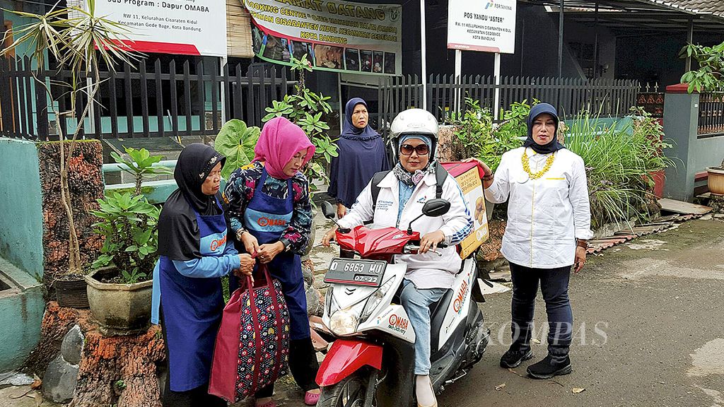 Ibu-ibu kader posyandu di RW 011 Kelurahan Cisaranten Kidul, pinggiran Kota Bandung, mendirikan Omaba, yakni ojek pengantar makanan untuk anak balita yang kekurangan gizi. Nok AS Fauzi (54) bersiap mengantar makanan untuk anak-anak dari keluarga miskin di perkampungan Cekungan Bandung itu, Rabu (13/12).