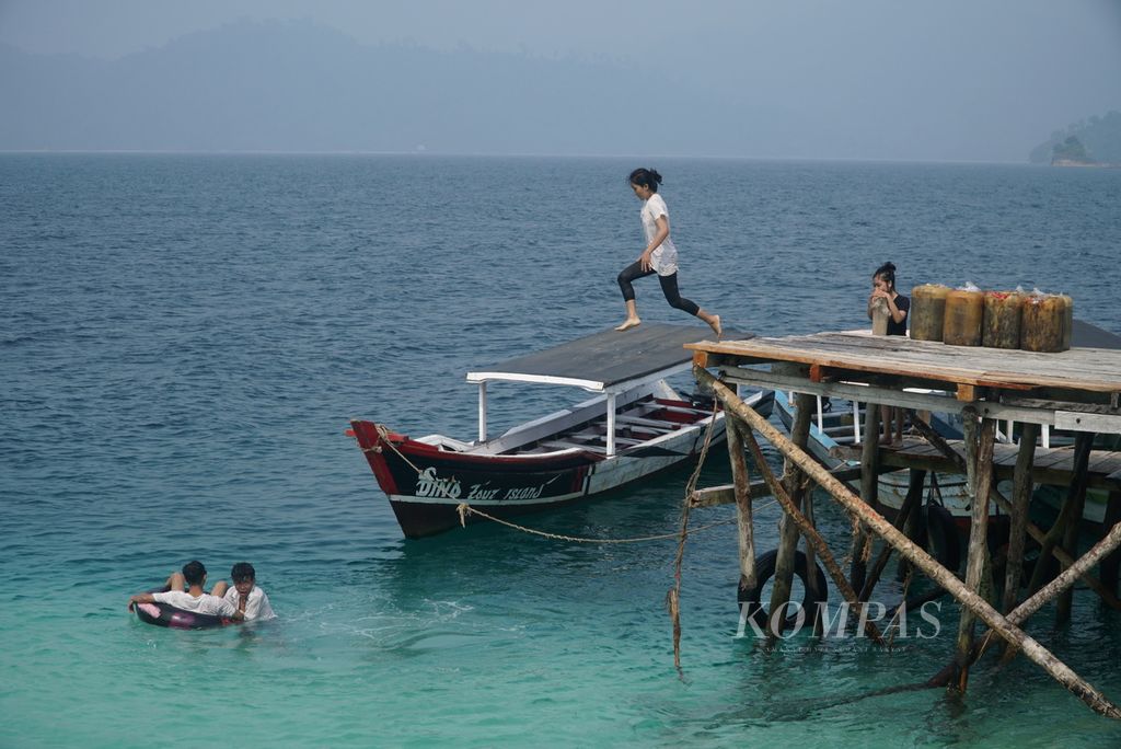Pengunjung terjun ke laut dari atas Dermaga Pulau Sirandah, Kelurahan Teluk Kabung Selatan, Kecamatan Bungus Teluk Kabung, Kota Padang, Sumatra Barat, Sabtu (7/10/2023). 