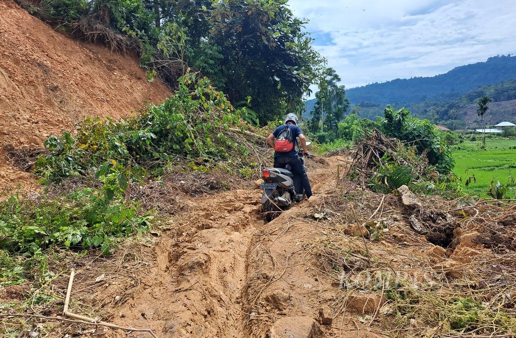 Seorang pengendara kesulitan melintasi bekas longsor di Kampung Batu Bala, Nagari Ganting Mudiak Utara Surantih, Kecamatan Sutera, Kabupaten Pesisir Selatan, Sumatera Barat, Selasa (12/3/2024). 