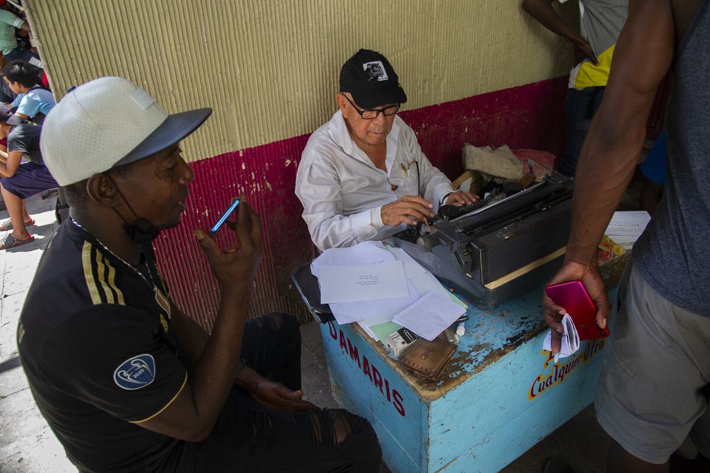 Seorang pria dibayar untuk mengisi formulir pendataan para migran yang merupakan bagian dari karavan menuju AS, di alun-alun utama Tapachula, Negara Bagian Chiapas, Meksiko, Selasa (14/9/2021). 