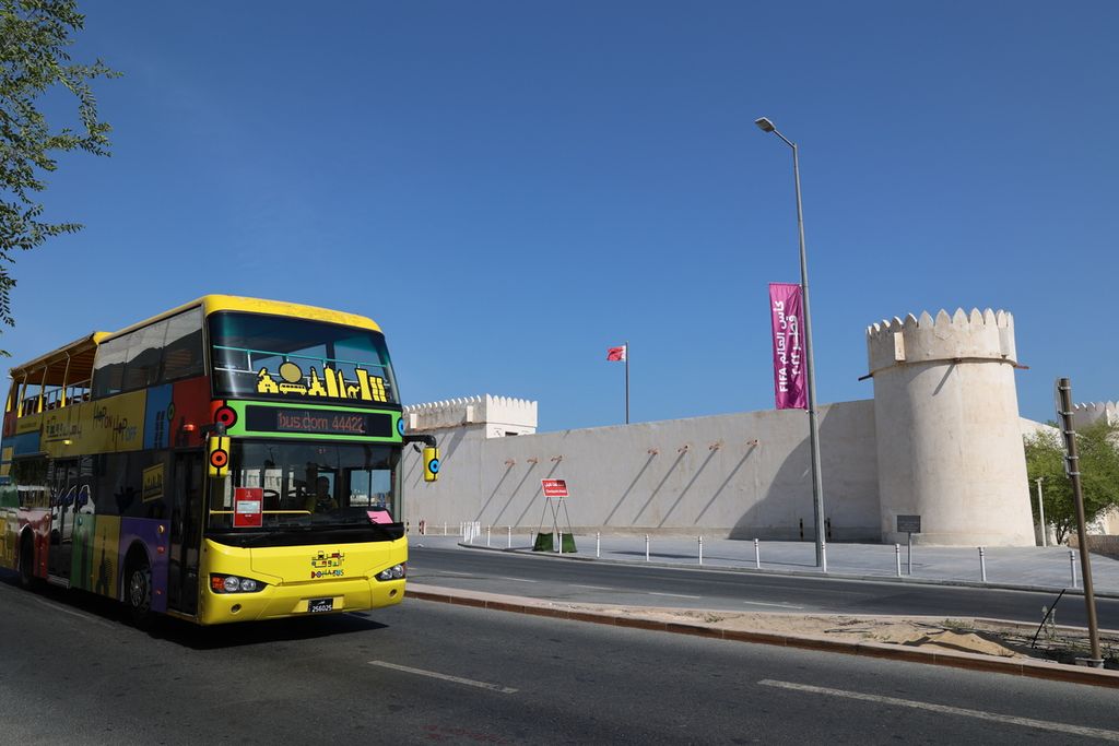 Bus melewati bendera Piala Dunia 2022 yang terpasa di depan Benteng Al Koot, salah satu tempat bersejarah di kawasan Msheireb, kota Doha, Qatar (17/11/2022). Moblitas warga dan suporter dari berbagai negara meningkatkan konsumsi BBM transportasi publik.