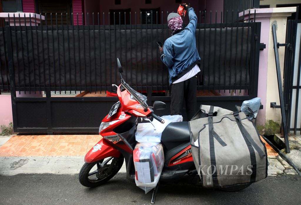 Kurir ekspedisi menyerahkan barang ke pelanggan di kawasan Duren Sawit, Jakarta, Selasa (5/4/2022). Kurir mengambil barang yang didistribusikan dari gudang ke titik <i>base camp </i>dan diantar ke alamat pelanggan. 