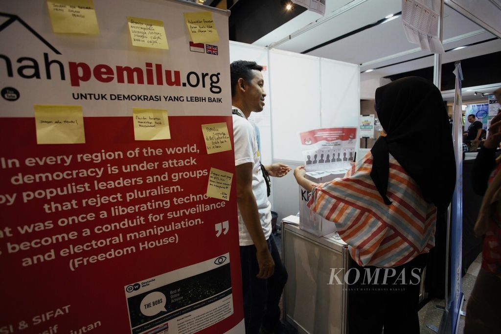 Anggota Perkumpulan untuk Pemilu dan Demokrasi (Perludem) memperlihatkan contoh surat suara untuk calon anggota Dewan Perwakilan Daerah (DPD) kepada pengunjung dalam acara sosialisasi melawan hoaks terkait pemilu di Gedung Sarinah, Jakarta, Minggu (24/12/2023).