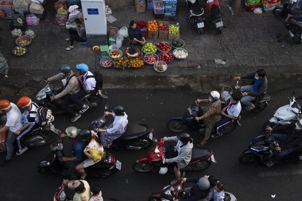 Pengendara sepeda motor melintasi pedagang saat jam sibuk di Ho Chi Minh City, Vietnam, 12 Januari 2024. Laporan Bank Dunia pada 1 April 2024 menyebut, perekonomian Asia diperkirakan tumbuh 4,5 persen tahun ini. 