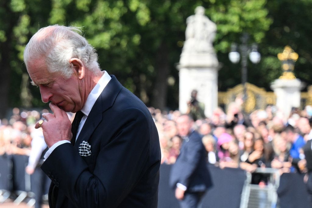 Raja Inggris Charles III mengamati berbagai karangan bunga di luar Istana Buckingham, London, Jumat (9/9/2022). Bunga-bunga diletakkan oleh warga sebagai tanda ikut berduka cita atas kepergian Ratu Elizabeth II, ibu dari Charles III.   
