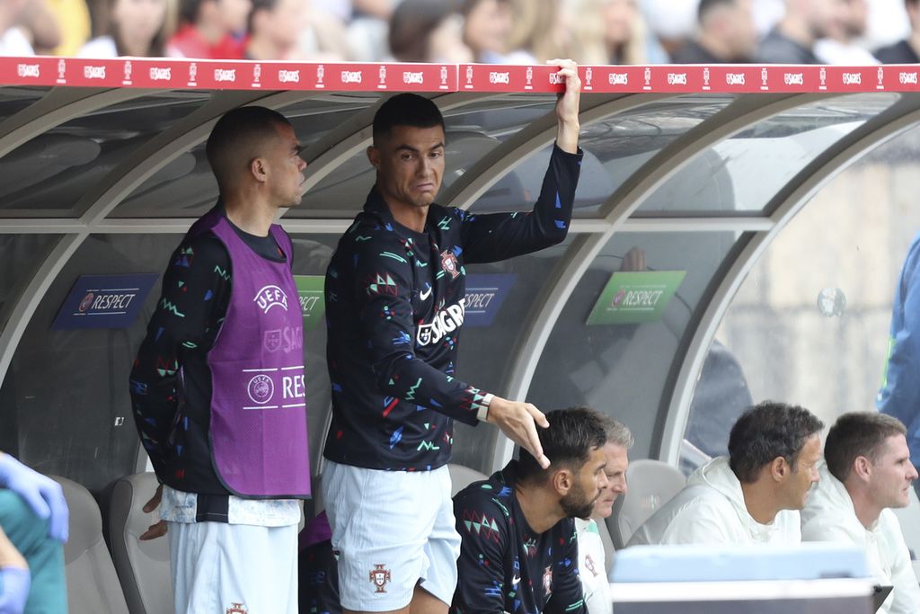 Penyerang Portugal, Cristiano Ronaldo (kanan), di bangku cadangan bersama Pepe saat laga uji coba Portugal lawan Kroasia di Oeiras, Portugal, Sabtu (8/6/2024). Ronaldo tidak dimainkan pada laga persiapan Piala Eropa 2024 ini.