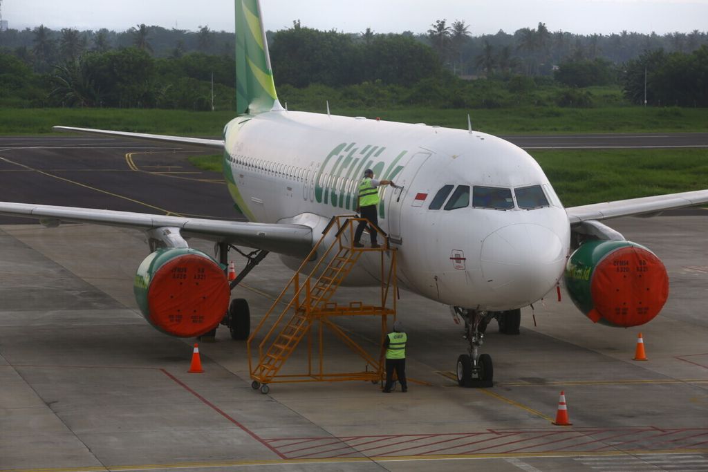 Petugas menutup baling-baling pesawat Citilink yang batal terbang akibat sebaran abu vulkanik Gunung Raung di Bandara Banyuwangi, Minggu (7/2/2021). Erupsi Gunung Raung menyebabkan Bandara Banyuwangi ditutup dan tujuh penerbangan dibatalkan.