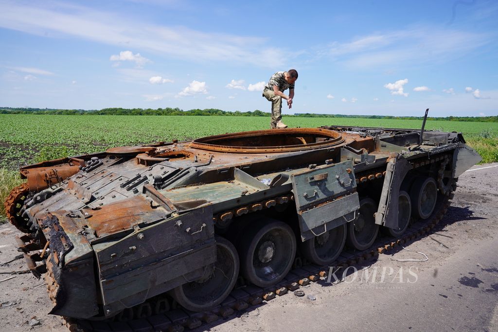 Anggota pertahanan teritorial melihat tank Rusia yang hancur di tepi jalan di Provinsi Sumy, Ukraina, Minggu (26/6/2022). Dalam beberapa hari terakhir, Rusia mengintensifkan serangan rudal ke Ukraina. Wilayah Ukraina yang diserang pun meluas.