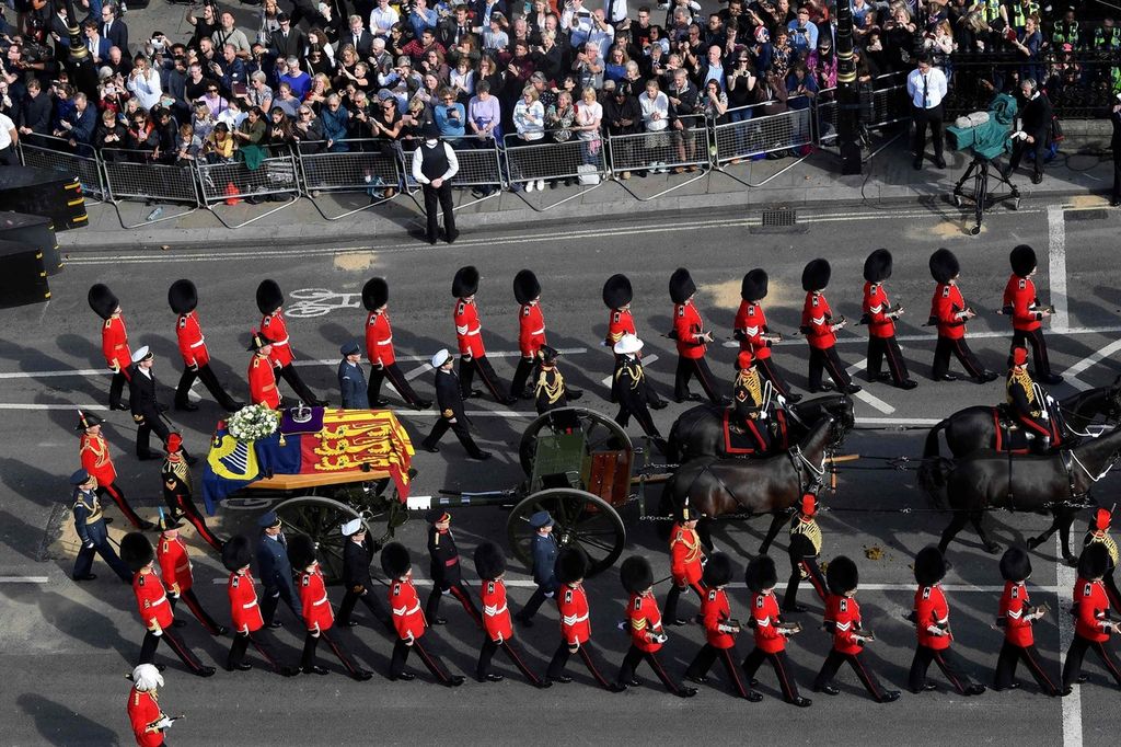 Guardsmen march beside the coffin of Queen Elizabeth II, adorned with a Royal Standard and the Imperial State Crown and pulled by a Gun Carriage of The King's Troop Royal Horse Artillery, during a procession from Buckingham Palace to the Palace of Westminster, in London on September 14, 2022. - Queen Elizabeth II will lie in state in Westminster Hall inside the Palace of Westminster, from Wednesday until a few hours before her funeral on Monday, with huge queues expected to file past her coffin to pay their respects. (Photo by TOBY MELVILLE / POOL / AFP)