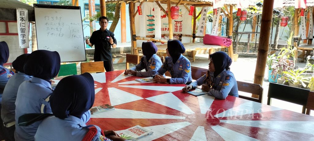 Sejumlah siswa SMK Puger di Jember, Jawa Timur, Kamis (19/10/2023), belajar bahasa Jepang bersama guru di halaman belakang sekolah. Sebagian besar lulusan SMK Puger bekerja di luar negeri, salah satunya Jepang. 