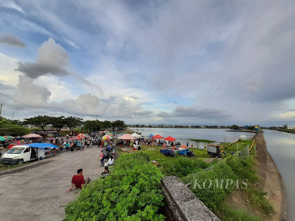 Keramaian warga dan pedagang jajanan di tepi Waduk Tunggu Pampang, Kota Makassar, Sulawesi Selatan, Selasa (21/3/2023).