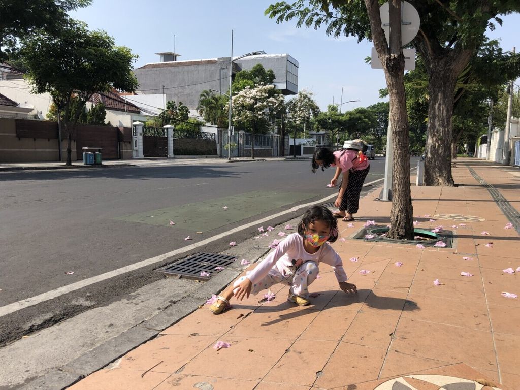 Anak-anak bermain dengan bunga tabebuya yang berguguran di trotoar Jalan Raya Gubeng, Surabaya, Jawa Timur, beberapa waktu lalu. Keberadaan trotoar penting bagi metropolitan seperti Surabaya karena sudah menjadi kebutuhan dan hak warga. 