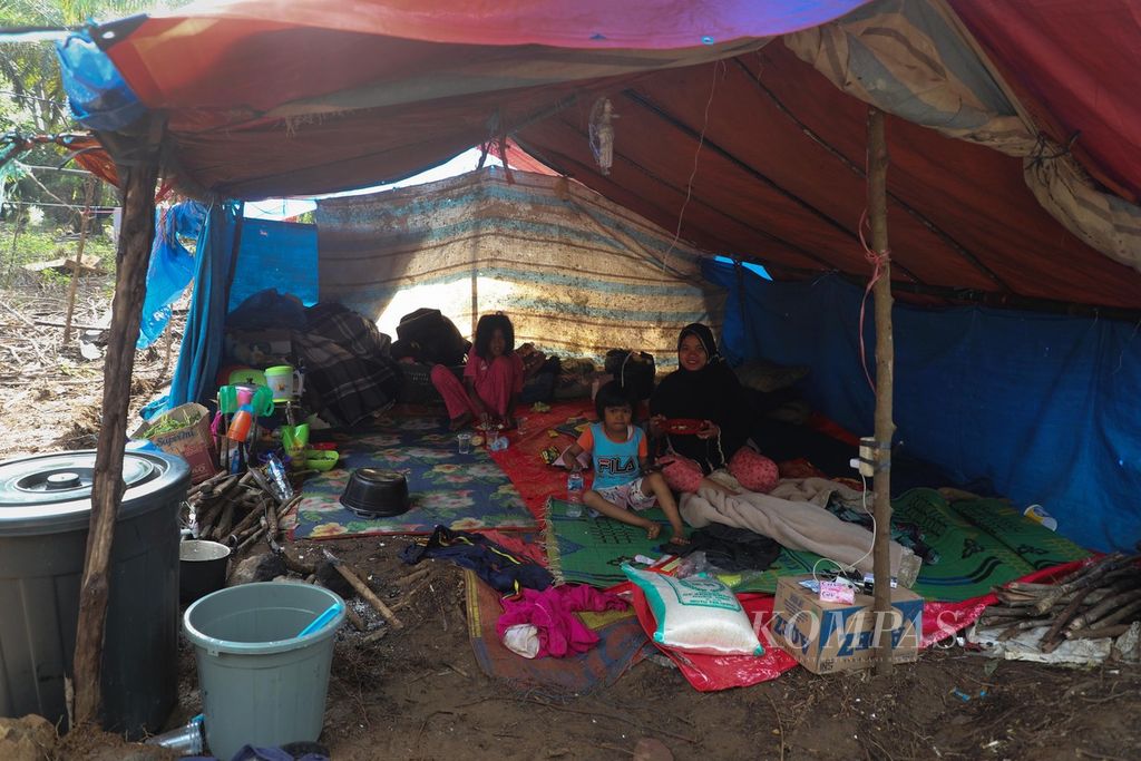 Pengungsi duduk di dalam tenda di tengah kebun sawit di Nagari Kajai, Kecamatan Talamau, Kabupaten Pasaman Barat, Sumatera Barat, Rabu (2/3/2022). Kebun sawit dipilih sebagai tempat mengungsi korban gempa bermagnitudo 6,1 dikarenakan dianggap lebih aman jika ada gempa susulan. 