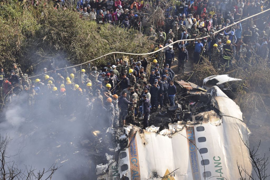 Regu penyelamat dan sejumlah warga sipil mencoba mencari korban selamat dalam kecelakaan pesawat Yeti Airlines di Pokhara, Nepal, Minggu (15/1/2023). Otoritas Penerbangan Sipil Nepal (CAAN) memastikan bahwa kotak hitam telah ditemukan dan dikirim untuk dianalisis. (AP Photo/Krishna Mani Baral)