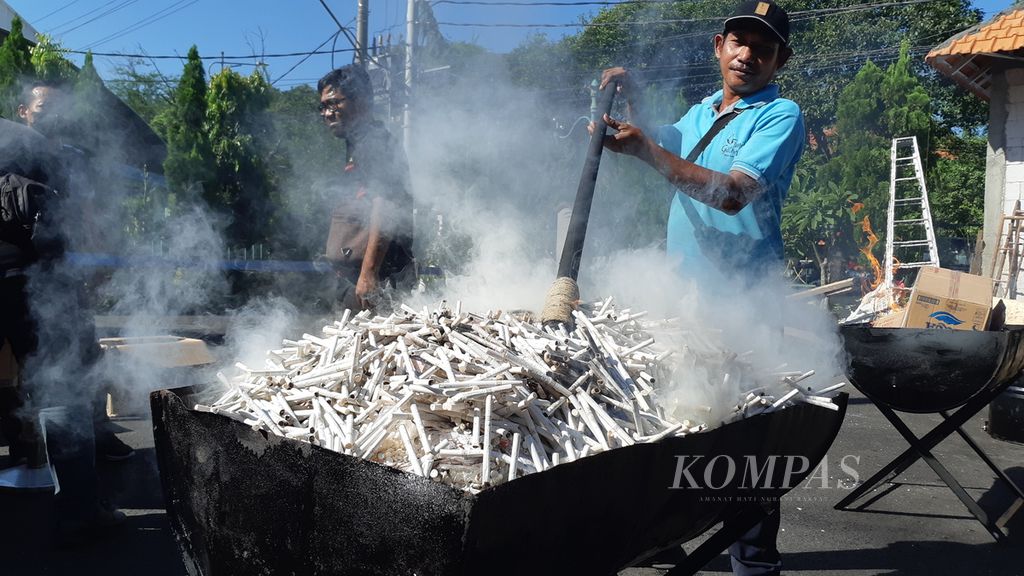 Pekerja berupaya membakar rokok ilegal. Sebanyak 27 karton rokok tanpa pita cukai yang diperoleh dari pengungkapan kasus perdagangan rokok ilegal dimusnahkan oleh Kejaksaan Negeri Sidoarjo, Rabu (22/6/2022) 