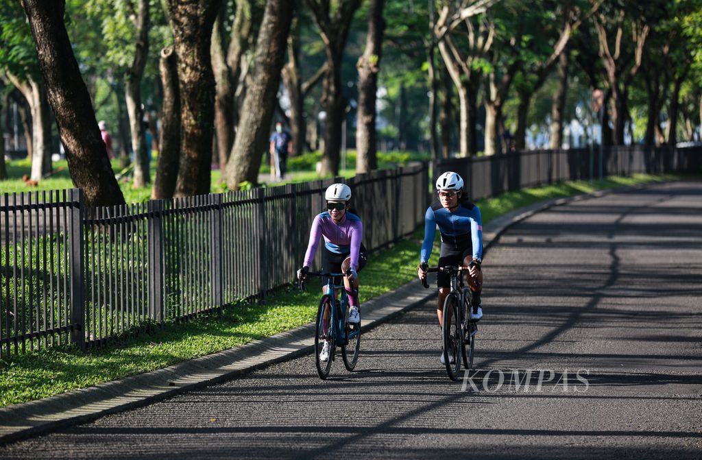 Pasangan suami-istri Ari Saputra dan Roslina Saputra (kiri) bersepeda di kawasan perumahan Bintaro, Tangerang Selatan, Banten, Jumat (13/5/2022). Setiap pagi, pasangan suami-istri ini rutin bersepeda untuk menjaga kebugaran dan berat badan.