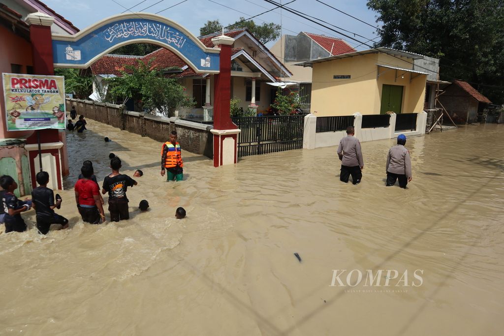 Warga melewati banjir luapan Sungai Ciberes di Desa Gunungsari, Kecamatan Waled, Kabupaten Cirebon, Jawa Barat, Sabtu (22/1/2022) siang. Sekitar 850 rumah warga terendam. Selain karena hujan deras, banjir juga dipicu penyempitan sungai.