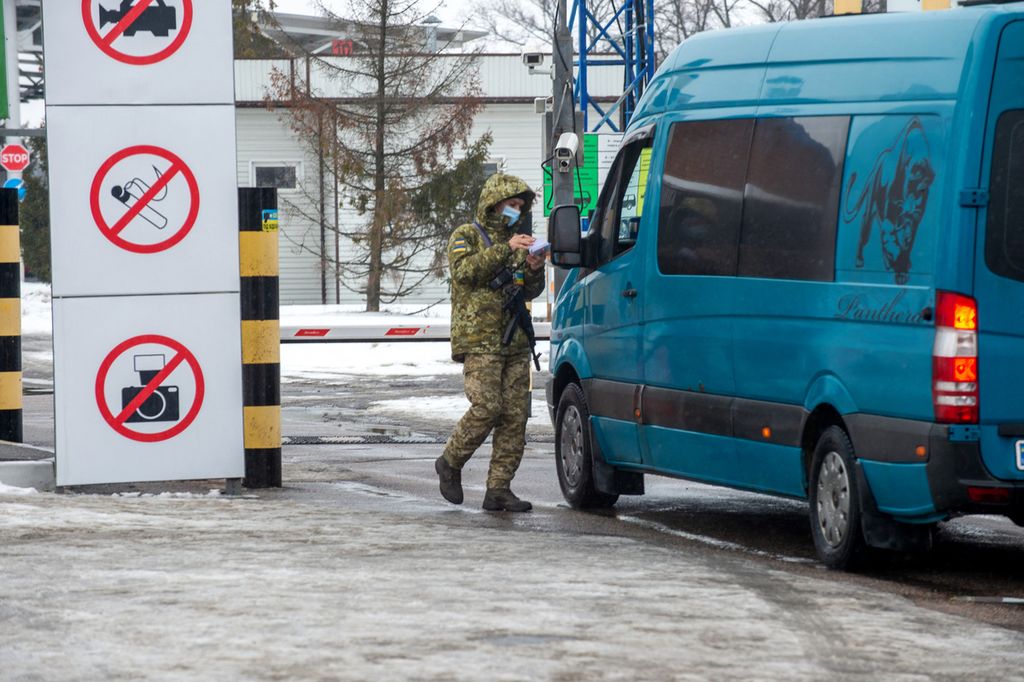 Penjaga perbatasan Ukraina memeriksa dokumen seorang pengemudi di perbatasan Ukraina-Rusia di pos pemeriksaan Goptivka, sekitar 40 km dari kota terbesar kedua di Ukraina, Kharkiv, Senin (7/2/2022).