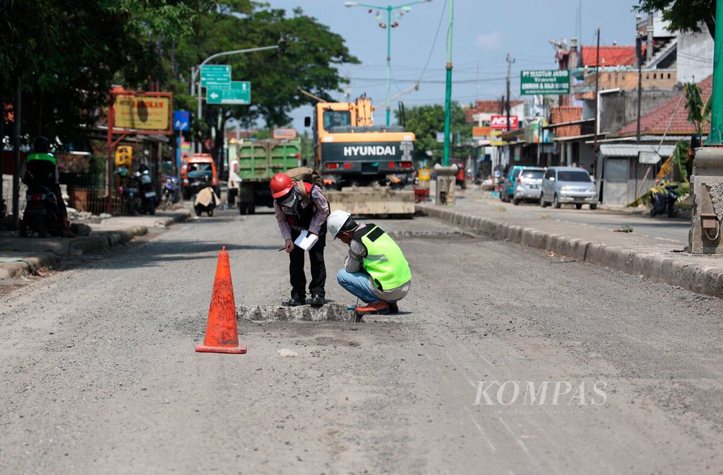 Pekerja saat memeriksa kondisi jalan yang rusak sepanjang jalur pantura Demak-Kudus setelah terdampak banjir di Kecamatan Karanganyar, Kabupaten Demak, Jawa Tengah, Minggu (24/3/2024). 